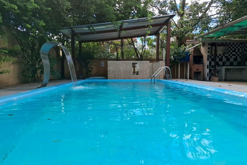 Piscina do Casarão do Indaiá com cascata e churrasqueira ao fundo